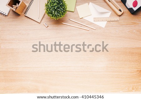 Topview of wooden desk with office tools and plant. Mock up