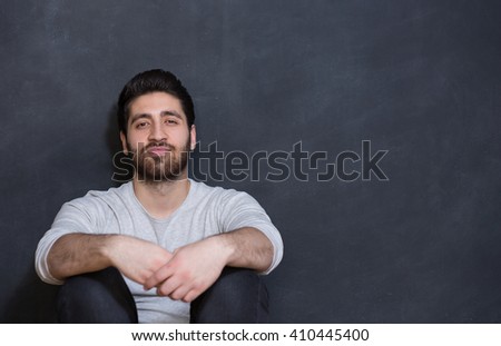 a young man with a beard on a chalkboard background with the emotion on his face