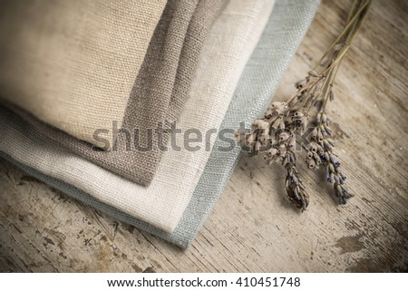 A pile of four folded dull-colored cotton fabric by a stalk of dried blossoms Royalty-Free Stock Photo #410451748