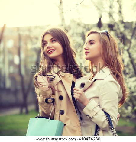 Consumerism, tourism and fashion concept - two beautiful girls going shopping. Outdoors, lifestyle toned image.