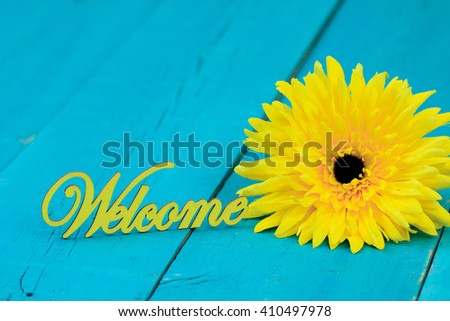 Welcome sign by yellow sunflower on antique rustic teal blue background