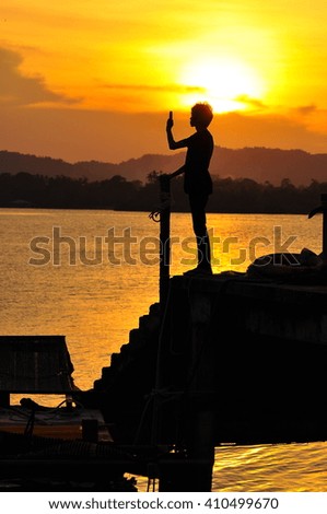 A silhouette of man taking photos of sunset with mobile phone with the background of orange sunset. stock photo . copy space
