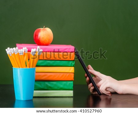 Hands using tablet computer near empty green chalkboard