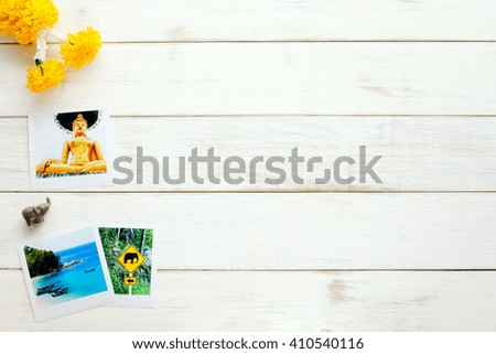 Thai background. Memories of Thailand / travel planning. Travel photos, clay elephant, marigold garland on a white table. 