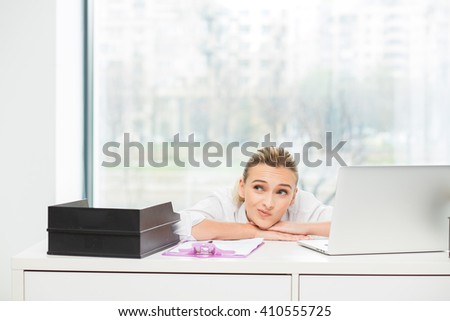 blonde woman lying on her desk and thinking at solutions