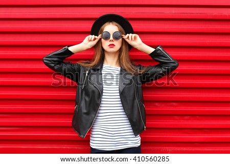 Fashion portrait pretty woman in black rock style over red background Royalty-Free Stock Photo #410560285