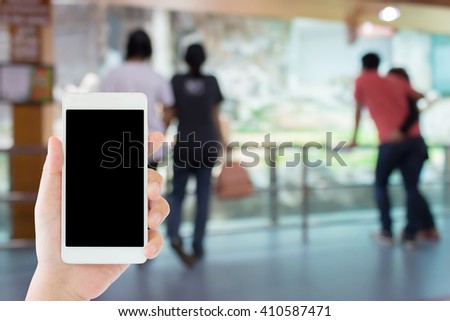 woman use mobile phone and blurred image of people in the indoor zoo