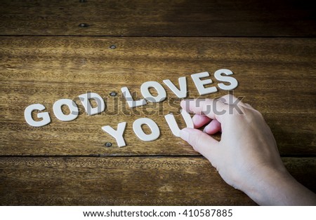 word "God loves you" design  by white wooden letter press on wooden table, concept