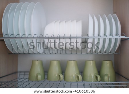 Plate rack with clean dishware Royalty-Free Stock Photo #410610586
