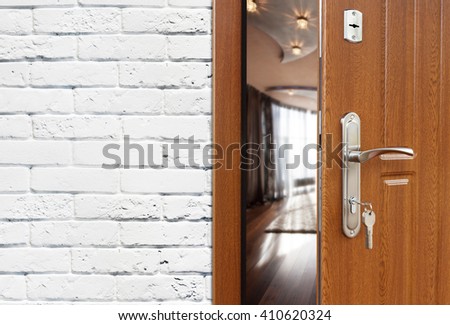 Half opened door to a living room at white brick wall, modern interior design. Handle and lock. Lounge room entrance. Welcome, privacy concept.  