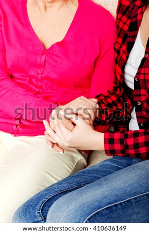 Mother and daughter sitting on couch and holding hands 