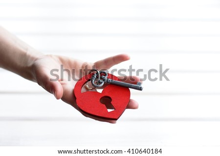 red wooden heart-shaped lock with a key on the hand/An offer of marriage