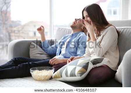 Young couple watching TV on a sofa at home Royalty-Free Stock Photo #410648107