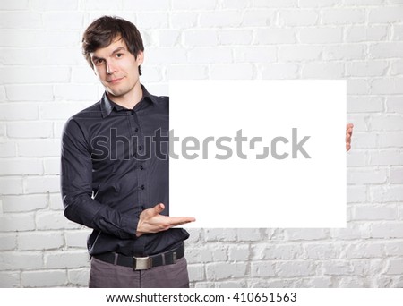 young man holding poster in brick room