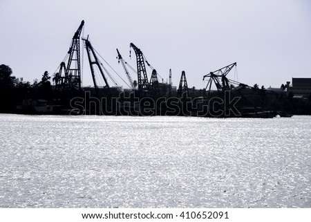 Silhouette crane and oil rig near  river