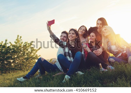 Group of young people taking a selfie outdoors, having fun  