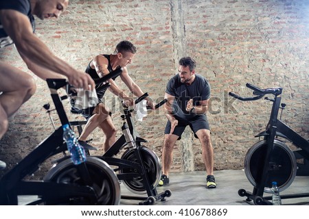 
Fit young people on exercise bicycle  Royalty-Free Stock Photo #410678869