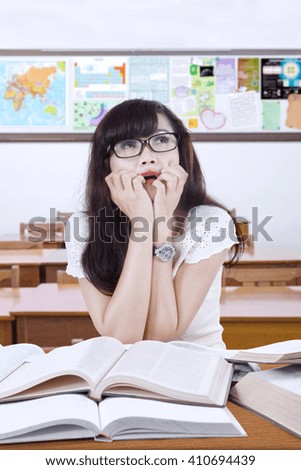 Photo of a female high school student studying in the classroom and looks stressful while preparing exam