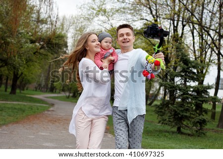Happy young family taking selfies with her camera on the gimbal steadycam