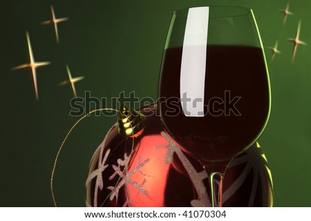 a glass of red wine and christmas decoration