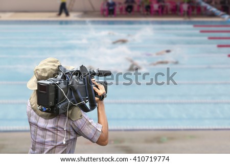 Video cameraman operator with competition swim pool in swimming stadium.