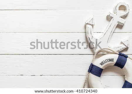 Anchor and lifebuoy on white wood table Royalty-Free Stock Photo #410724340