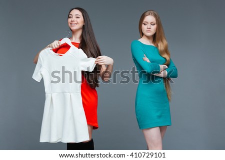 Happy cheerful young woman and envious angry female on shopping over grey background Royalty-Free Stock Photo #410729101