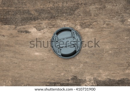 Camera lens cap on wood background