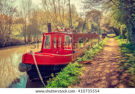 House boat in red at the Canal. Narrow boat moored on a stretch of the Grand Union Canal in Warwickshire, England, United Kingdom. Royalty-Free Stock Photo #410735554