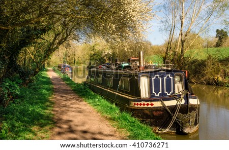 England - Inland Navigation. Barge moored on a stretch of the Grand Union Canal near Leamington Spa, in Warwickshire, England, United Kingdom. Royalty-Free Stock Photo #410736271