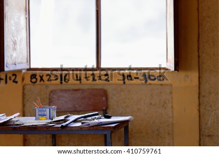 Teacher.s chair-table with school supplies -textbooks-notebooks-pencils-. Classroom using walls as blackboard for writing teachings. Berahile-market for the salt from the Danakil. Afar region-Ethiopia
