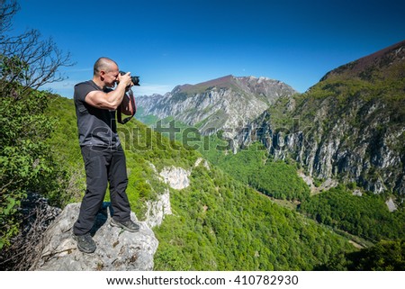 Professional nature photographer hiking on a trail in mountains