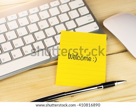Welcome with smily face on sticky note on work table Royalty-Free Stock Photo #410816890