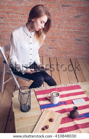 Beautiful girl working behind the plate at the table . Brick background 