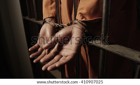 African American Man in Prison - hands cuffed outside of bars Royalty-Free Stock Photo #410907025