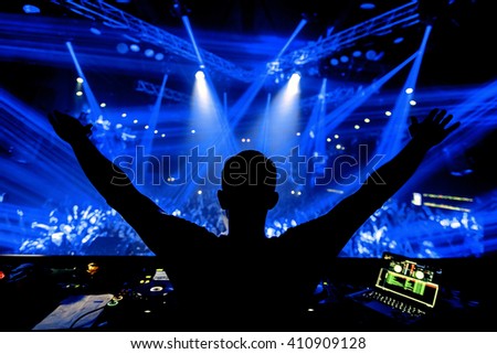 DJ hands up at night club party under blue light with crowd of people Royalty-Free Stock Photo #410909128