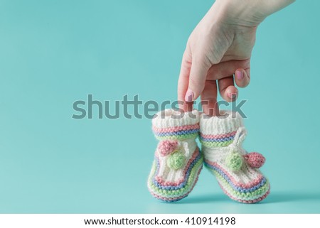 female hand holds small baby shoes Royalty-Free Stock Photo #410914198