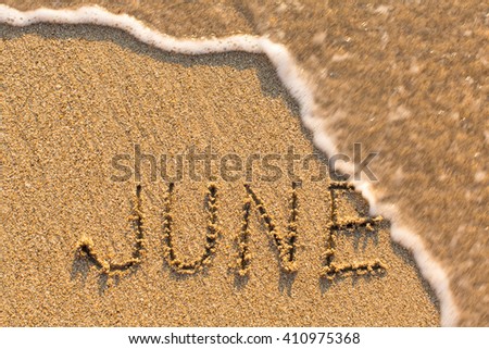 June - word drawn on the sand beach with the soft wave. Months series of 12 pictures. Royalty-Free Stock Photo #410975368