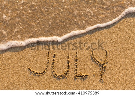 July - word drawn on the sand beach with the soft wave. Months series of 12 pictures.