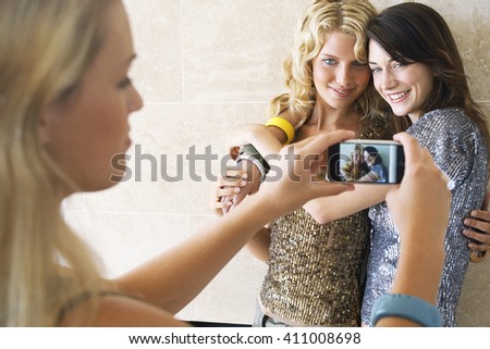 friends taking photos with a smart phone and showing the photo in the screen 
