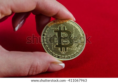Golden Bitcoins (digital virtual money) in hand on red background.