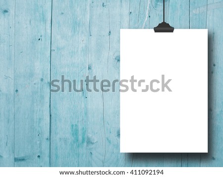 Close-up of one blank frame hanged by clip against aqua, weathered wooden background