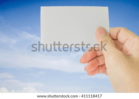 concept photo of right hand hold business card, credit card or blank paper on blurred blue sky with white cloud