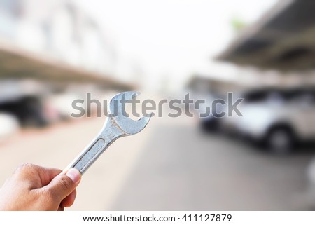 Hand hold wrench in park car  blur concept idea.