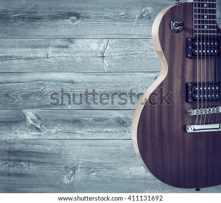 Part of the orange electric guitar on wooden background. A place for writing of the text