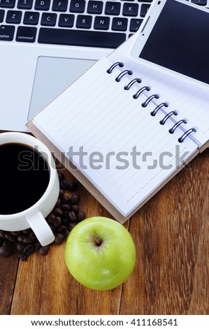 Notebook,smartphone,notepad and a cup of coffee on wooden table