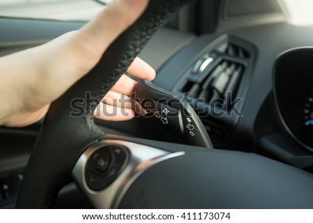 Closeup photo of woman driving car and using turn signal switch Royalty-Free Stock Photo #411173074