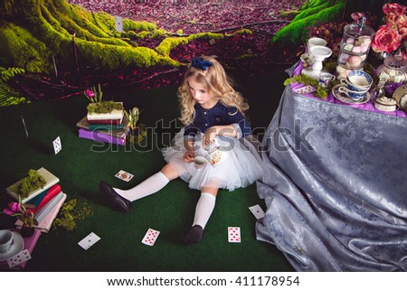 Little girl as Alice in Wonderland pouring tea