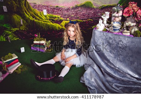 Little sitting on the floor girl as Alice in Wonderland 