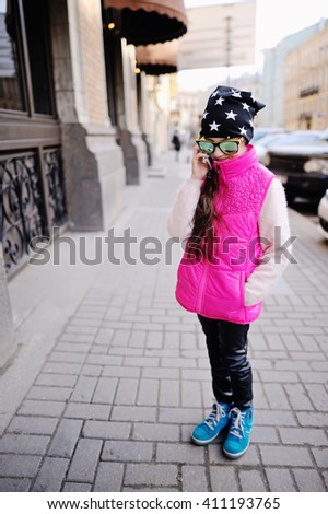 Happy fashion preteenkid  girl  talking on smartphone in city street
